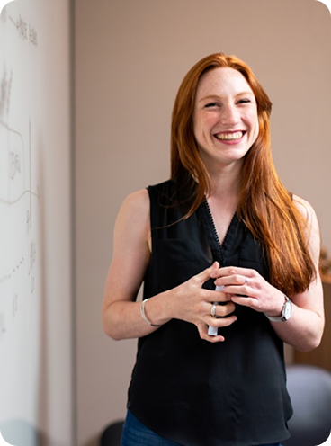 Mujer sonriente en una sala de reuniones, imagen que representa cercanía, profesionalismo y el lado humano del equipo detrás de las Branded Residences.