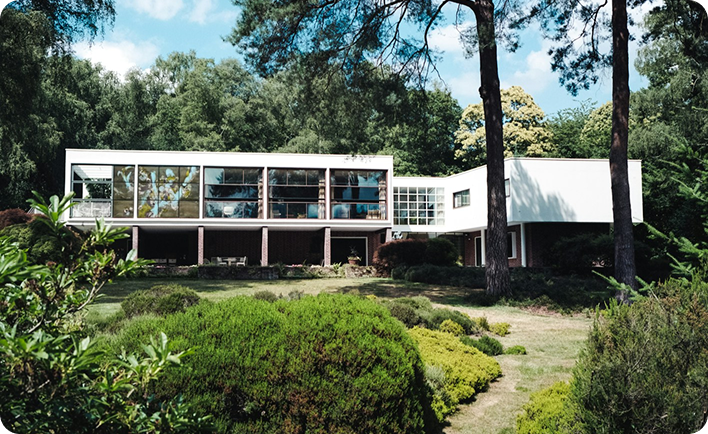 Residencia de lujo moderna integrada en entorno forestal, con fachada acristalada y diseño horizontal, ejemplo de Branded Residence en zona verde.